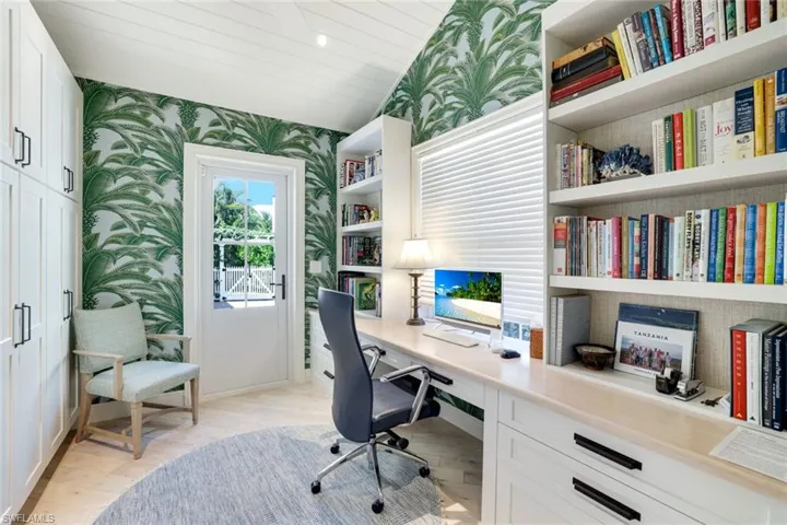 Office area with wallpapered walls, built in desk, light wood-style floors, wooden ceiling, and recessed lighting
