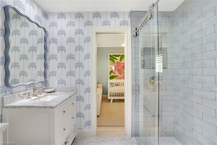 Ensuite bathroom featuring wallpapered walls, a stall shower, and vanity