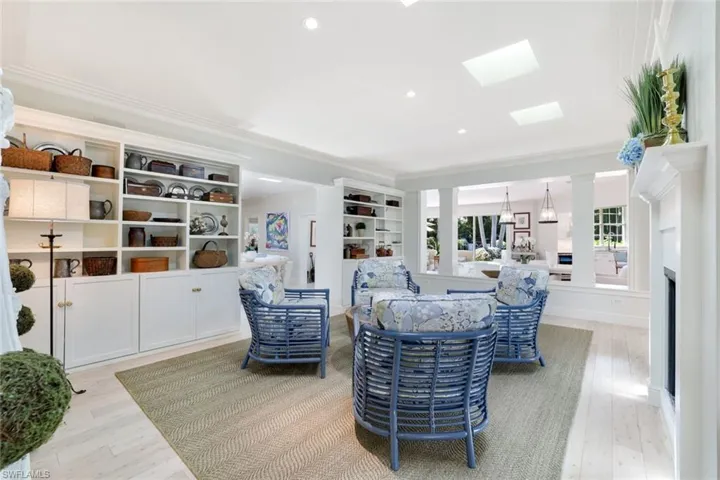 Living room featuring light wood-type flooring, ornamental molding, recessed lighting, a skylight, and a fireplace