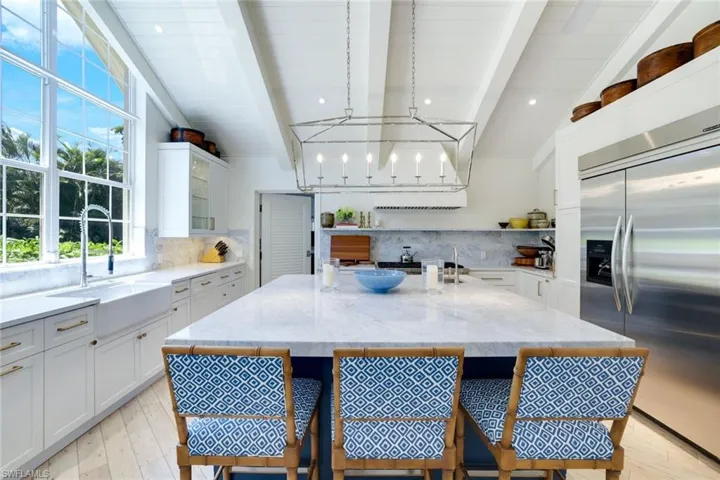 Kitchen with white cabinetry, a kitchen breakfast bar, built in fridge, and beamed ceiling