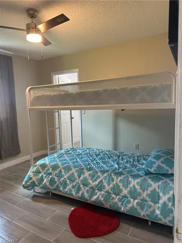 Room featuring plank-style tile flooring, light-toned wall paint, and a ceiling fan with integrated lighting