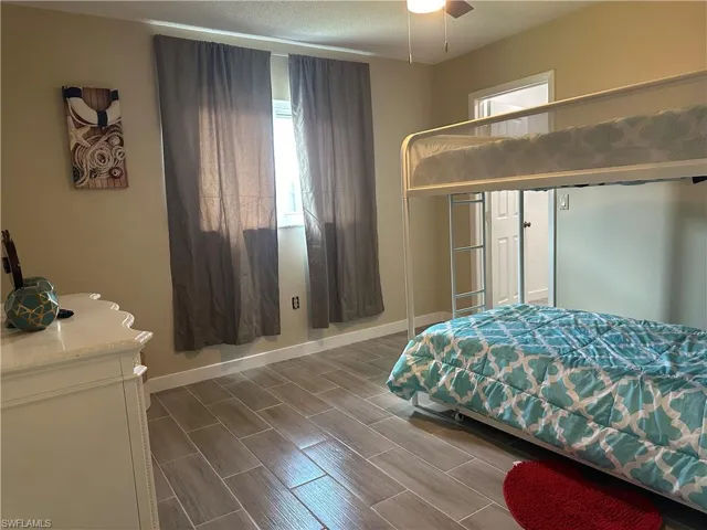 Room featuring wood-finish tile flooring, a window with drapery, light tan wall color, and a ceiling fan