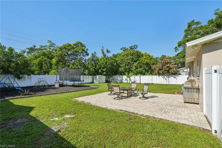 Fenced backyard with a trampoline and a patio area
