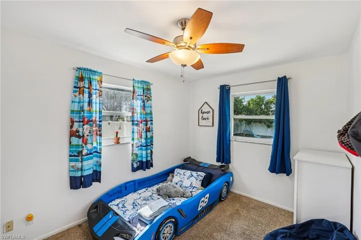 Carpeted bedroom with ceiling fan and baseboards