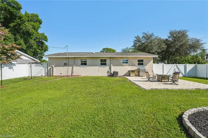 Rear view of house with a gate, a fenced backyard, stucco siding, and a patio area