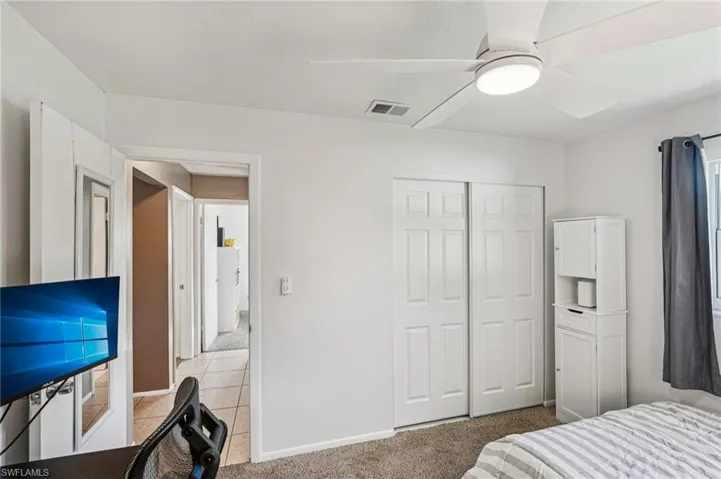 Bedroom featuring light colored carpet, a ceiling fan, and a closet