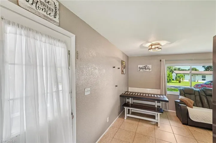 Hallway featuring a textured wall and light tile patterned floors