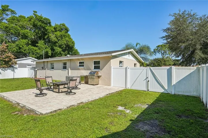 Back of house with a gate, a patio area, and stucco siding