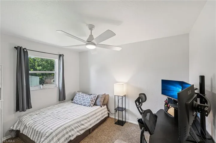 Carpeted bedroom with a ceiling fan, a textured ceiling, and a textured wall