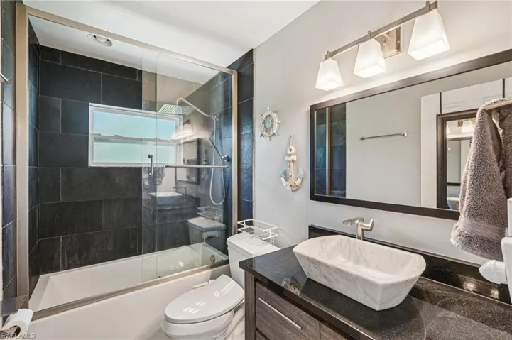 Bathroom with shower / bath combination with glass door and vanity