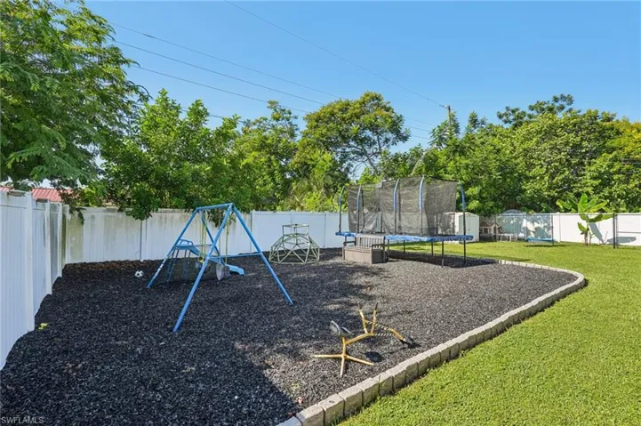 View of playground with a fenced backyard and a trampoline