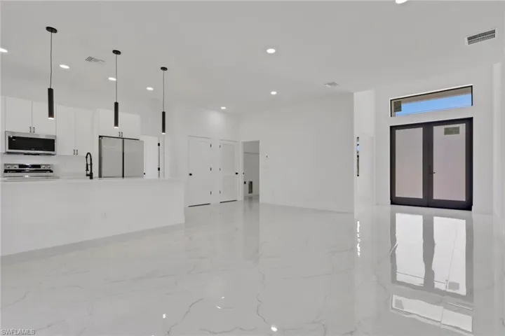 Living room, front door, kitchen, dining area, recessed lighting, and porcelain tile floor
