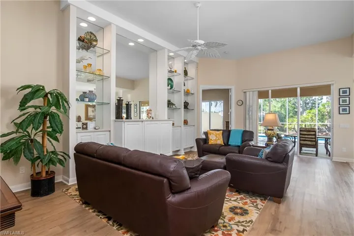 Living room with light Engineered waterproof flooring, custom built in features, and ceiling fan