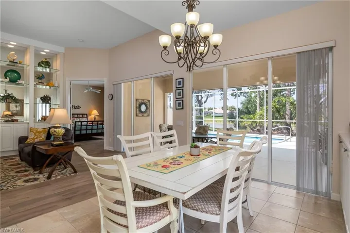 Dining room with chandelier and light tile floors looking onto water