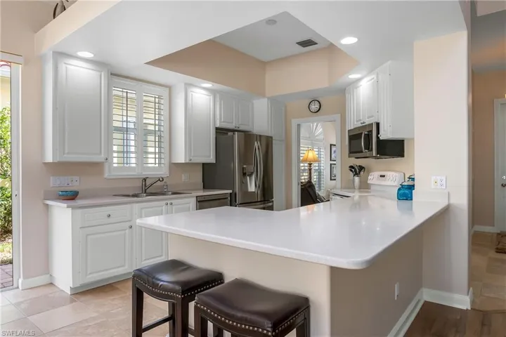 Kitchen with peninsula, a breakfast bar, white cabinets, and appliances with stainless steel finishes