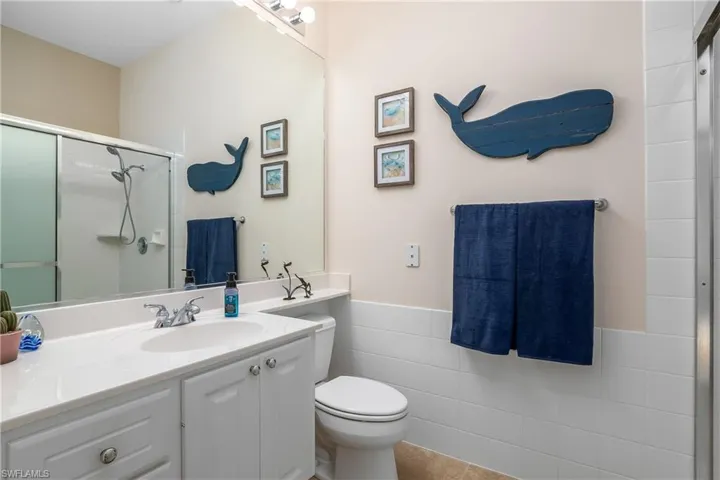 Bathroom area #2 of Primary suite featuring tile flooring, oversized vanity, toilet, shower and tile walls