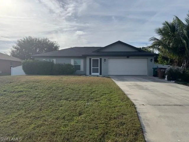 Ranch-style house featuring a front lawn, driveway, an attached garage, and stucco siding