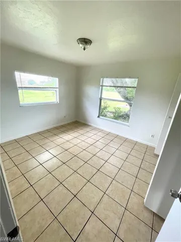 Empty room with light tile patterned floors and healthy amount of natural light