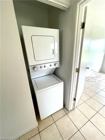Laundry room featuring light tile patterned floors and estacked washer and dryer