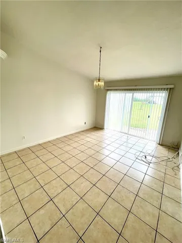 Spare room with a chandelier and light tile patterned flooring