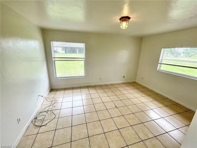 Unfurnished room featuring light tile patterned floors, healthy amount of natural light, and a textured ceiling