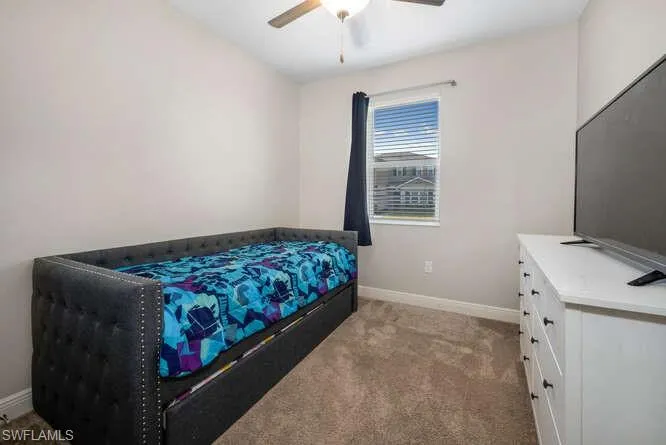 Carpeted bedroom featuring baseboards and ceiling fan