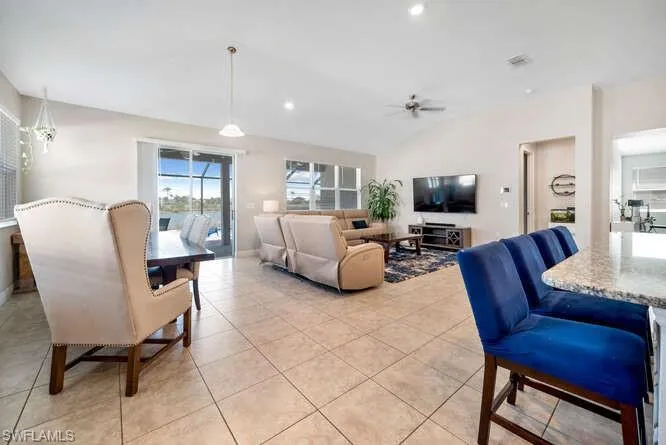 Living area with vaulted ceiling, recessed lighting, light tile patterned floors, and a ceiling fan