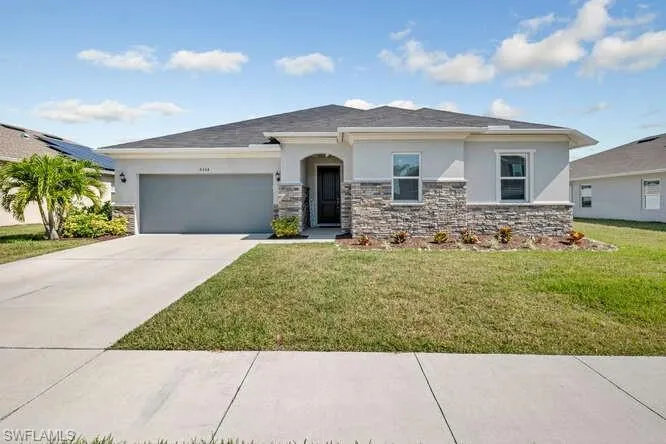 Prairie-style home with stone siding, stucco siding, an attached garage, and a front yard