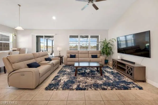 Tiled living area with lofted ceiling, recessed lighting, and a ceiling fan