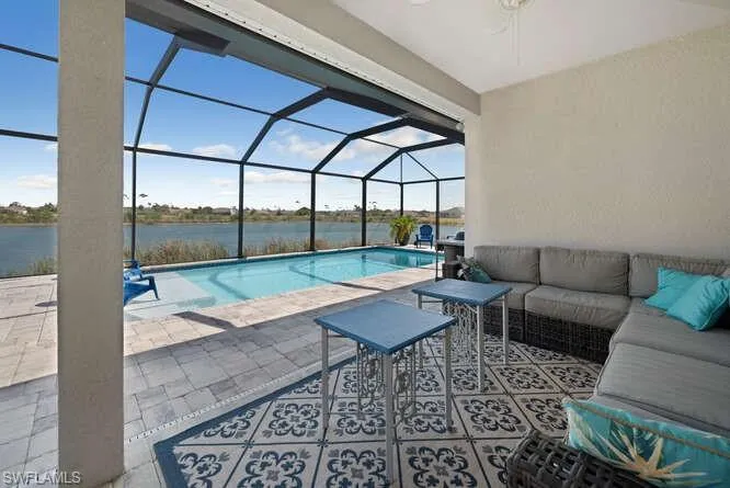 Outdoor pool featuring an outdoor hangout area, a water view, a patio, and glass enclosure