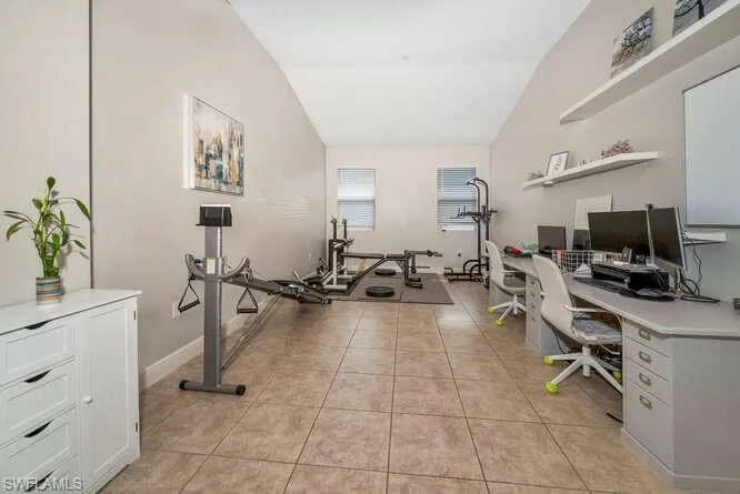 Exercise room featuring lofted ceiling and light tile patterned flooring