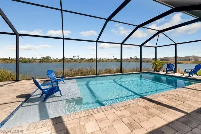 Swimming pool with a patio, a water view, and a lanai