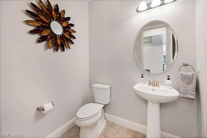Half bath with baseboards and tile patterned floors