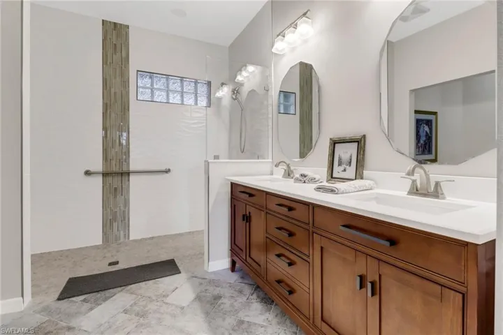 Bathroom featuring tiled shower, two sinks and separate room for smart toilet.