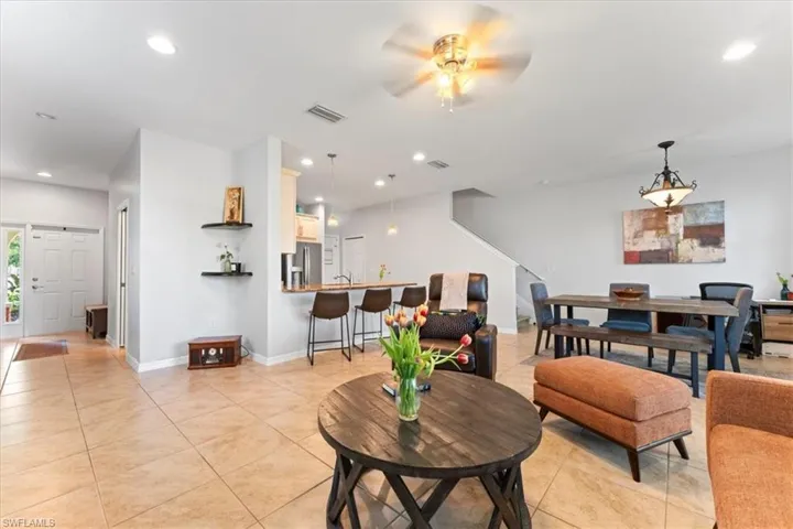 Living area featuring ceiling fan, light tile patterned floors, recessed lighting, baseboards, and stairway