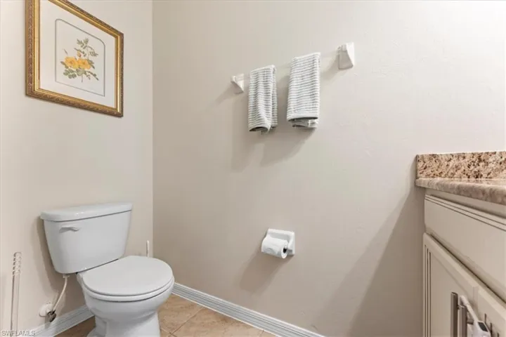Half bath with baseboards, vanity, toilet, and tile patterned flooring