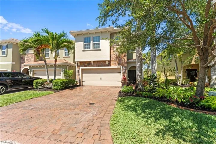 View of front of home featuring stone siding, decorative driveway, stucco siding, and an attached garage