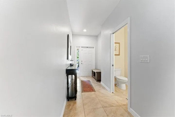 Hallway featuring light tile patterned floors, baseboards, and recessed lighting