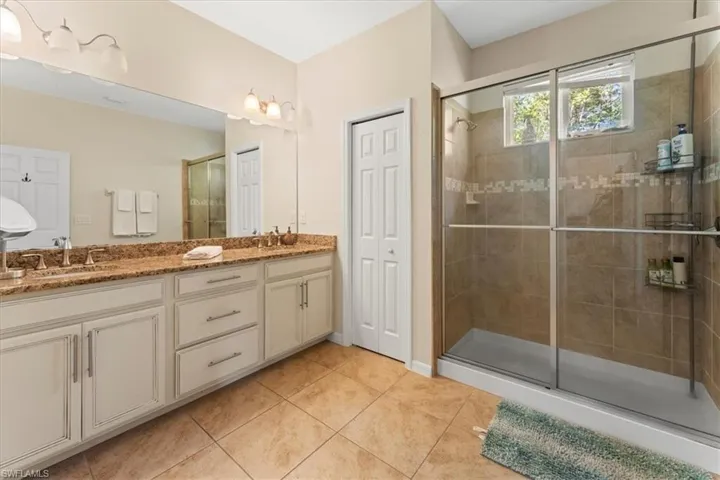 Bathroom with a shower stall, tile patterned floors, and double vanity
