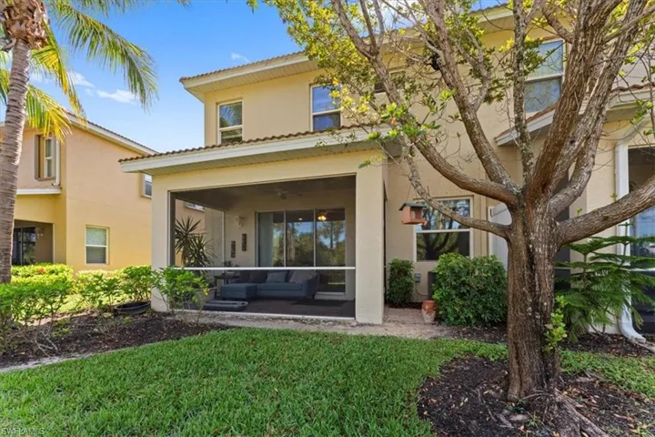 Rear view of property featuring stucco siding, a sunroom, and a tiled roof