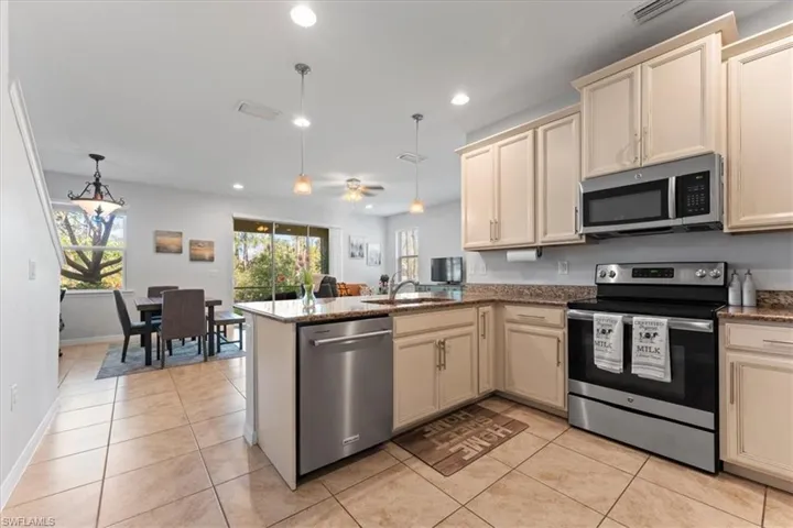 Kitchen with stainless steel appliances, cream cabinetry, a sink, and recessed lighting