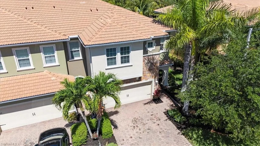 View of front facade with a tiled roof, an attached garage, and decorative driveway