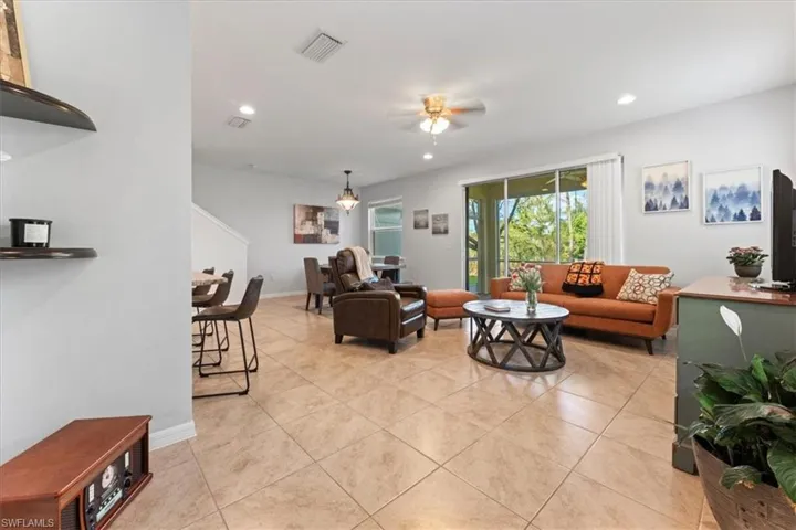 Living room with a ceiling fan, light tile patterned flooring, and recessed lighting