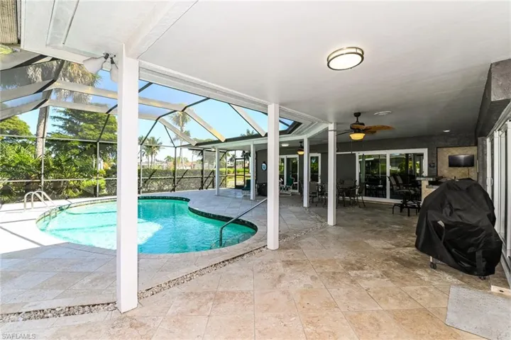 Swimming pool featuring a patio, a sunroom, outdoor dining area, grilling area, and glass enclosure