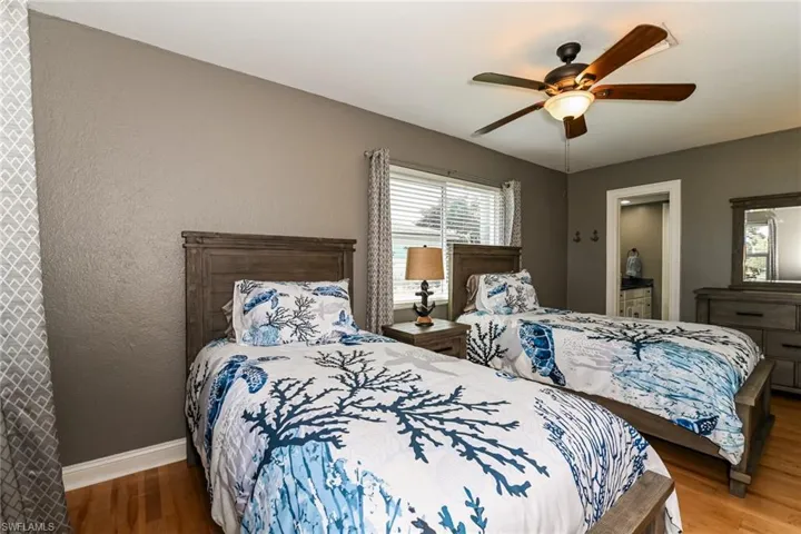 Bedroom featuring wood finished floors, ceiling fan, a textured wall, and connected bathroom