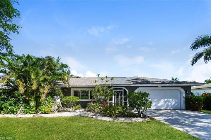 Ranch-style home featuring driveway, a garage, a front lawn, and stucco siding