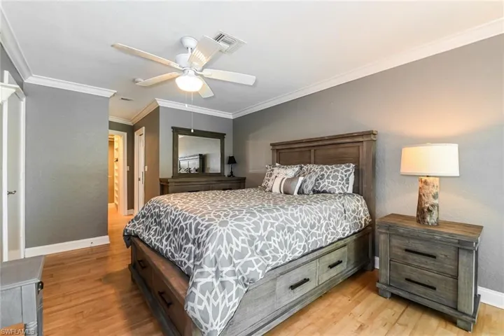 Bedroom with ornamental molding, light wood-style flooring, ceiling fan, a closet, and a textured wall