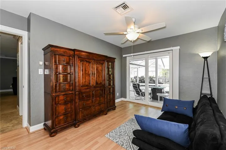 Living area with a textured wall, light wood-style floors, and ceiling fan