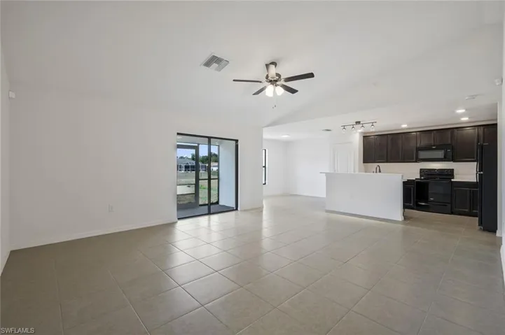 Unfurnished living room featuring ceiling fan, light tile patterned flooring, lofted ceiling, and recessed lighting