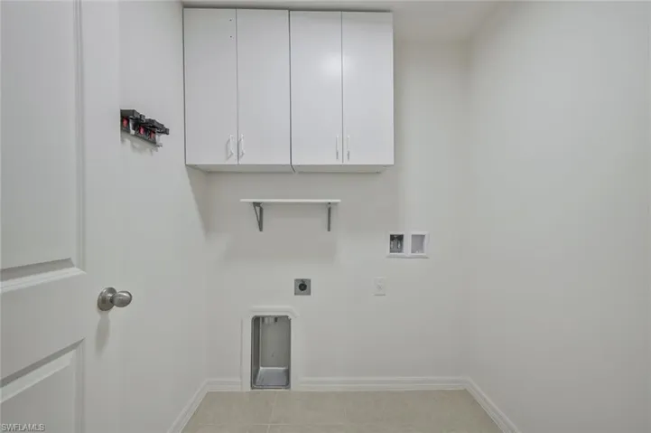 Laundry room with cabinet space, electric dryer hookup, washer hookup, and light tile patterned floors